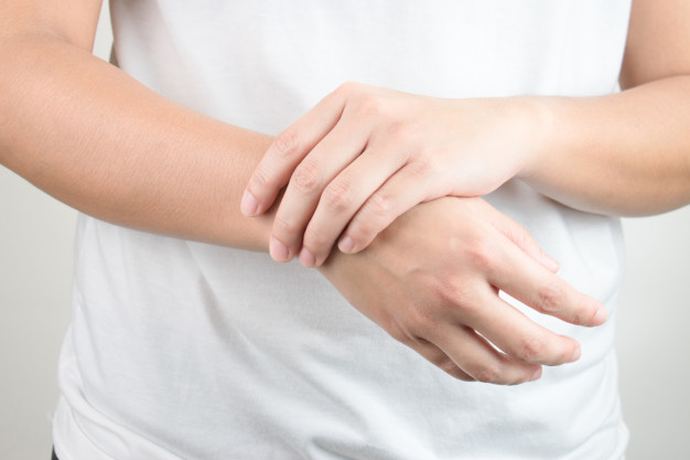 Gambar seseorang berbaju putih sedang mengecek perubahan ukuran tangan kananannya sebagai simbol salah satu gejala akromegali